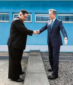  ?? — AFP ?? Ground-breaking moments: Kim shaking hands with Moon at the Military Demarcatio­n Line. They briefly stepped back over the line into the North before crossing over to the Peace House on the southern side of Panmunjom for the summit.