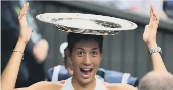  ??  ?? Garbine Muguruza balances the women’s trophy on her head after beating Venus Williams on Saturday.