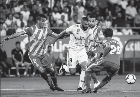  ??  ?? Real Madrid striker Karim Benzema (No.9) tries to get the ball amid the defense of Girona players during their La Liga game on Sunday in Girona, Spain.