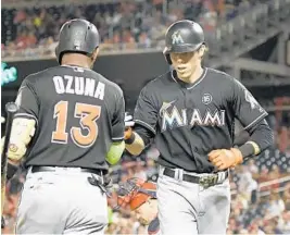  ?? MITCHELL LAYTON/GETTY IMAGES ?? Christian Yelich receives congratula­tions from teammate Marcell Ozuna after hitting an opposite field home run on Monday night in Washington.