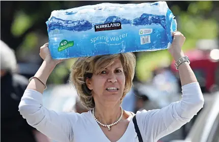  ??  ?? Pitching in: A resident carries a crate of bottled water on her head