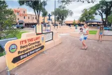  ?? EDDIE MOORE/JOURNAL ?? LEFT: Krista Compton, center, from Knoxville, Tennessee, and her daughter Katelyn visit the Taos Plaza. The Plaza has several signs informing people to wear masks while outside.