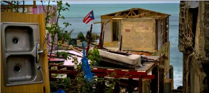  ??  ?? In this 2017 file photo, a Puerto Rican national flag is mounted on debris of a damaged home in the aftermath of Hurricane Maria in the seaside slum La Perla, San Juan, Puerto Rico. AP Photo/ RAmon EsPInosA