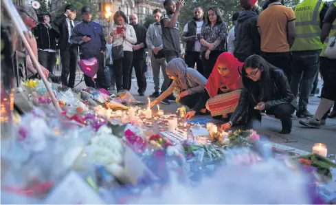  ?? AFP ?? People light candles in front of messages and floral tributes in Albert Square in Manchester on Tuesday, in solidarity with those killed and injured in the May 22 terror attack at the Ariana Grande concert at the Manchester Arena.