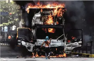  ??  ?? CARACAS: A truck set ablaze by opposition activists blocking an avenue during a protest burns in Caracas. —AFP