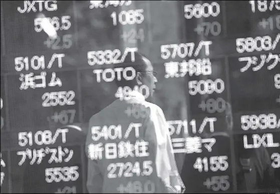  ?? REUTERS ?? Passersby are reflected in an electronic stock quotation board outside a brokerage in Tokyo, Japan.