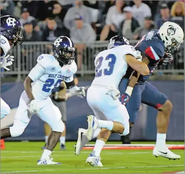  ?? STEPHEN DUNN/AP PHOTO ?? UConn running back Nate Hopkins, right, scores the first of his three touchdowns in the first quarter of the Huskies’ 27-20 win over Holy Cross on Thursday night in the season opener at Rentschler Field.