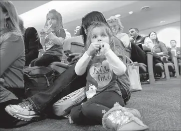  ?? Photograph­s by
Rich Pedroncell­i
Associated Press ?? ASHLEY WOOLEDGE sits near her mother and twin sister, Lexi, at a Senate Education Committee hearing last week on a bill to end exemptions from state-required immunizati­ons based on a “personal belief.”