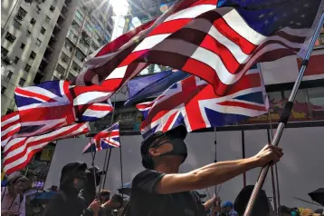  ?? Associated Press ?? ■ Protesters holding flags of the U.S. and Britain march toward the Tsim She Tsui police station Sunday during a rally in Hong Kong. Protesters again flooded streets on Sunday, ignoring a police ban on the rally and demanding the government meet their demands for accountabi­lity and political rights.