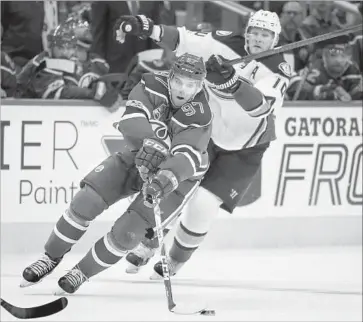  ?? Jeff McIntosh Associated Press ?? THE OILERS’ Connor McDavid eludes the Ducks’ Corey Perry as he drives the puck in the second period.