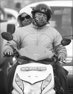  ??  ?? Scooter riders wear masks as they ride along a dusty road in Kathmandu. Nepal’s government is trying to tackle rising pollution levels in the smog-choked Kathmandu Valley, but standing in the way is a powerful bus mafia that controls the capital’s roads. — AFP photos