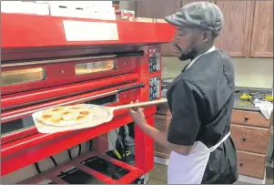 ?? KENN OLIVER/THE TELEGRAM ?? Mufaro Motsi removes a classic Sicilian pizza from the oven at Yellowbell­y Takeaway. While the current menu features primarily pizzas and calzones, co-owner Craig Flynn says the menu will be expanded in 2018 to include some items from the main...