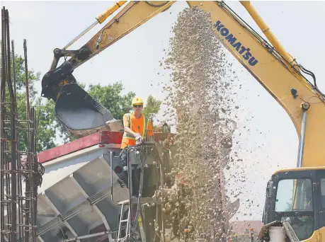  ?? DAN JANISSE ?? A worker drops material into the foundation of a building at a condominiu­m project Thursday on Banwell Road near Little River Boulevard.