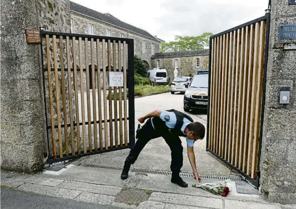  ?? SEBASTIEN SALOM-GOMIS / AFP ?? Un gendarme recull un ram dipositat a les portes de la comunitat montfortia­na de Saint-Laurent-sur-Sèvre, ahir