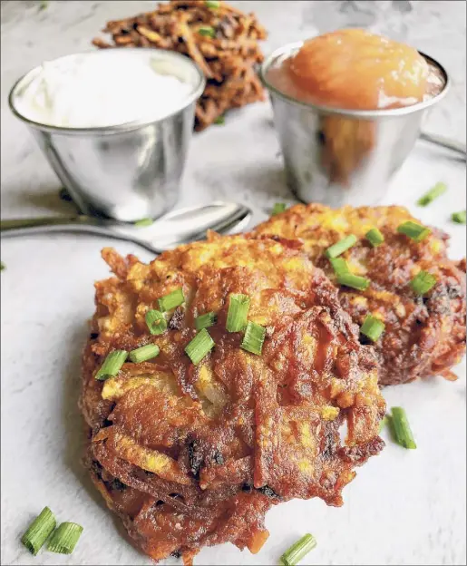  ?? Photo by Deanna Fox ?? Deanna Fox's latkes, served with her great-grandmothe­r's applesauce and sour cream. The key to crisp latkes is, surprising­ly, ice.