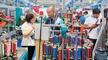  ?? Reuters-Yonhap ?? People visit the booth of a braiding machine producer from Xuzhou at the China Import and Export Fair, also known as Canton Fair, in Guangzhou, China, Tuesday.