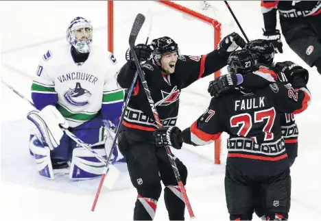  ?? GERRY BROOME/THE ASSOCIATED PRESS ?? Vancouver Canucks goaltender Ryan Miller looks on as Carolina Hurricanes left winger Joakim Nordstrom, centre, and pivot Elias Lindholm, right, congratula­te Justin Faulk after the defenceman’s goal during the third period on Tuesday in Raleigh, N.C.