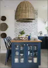  ?? RUSTIC WHITE PHOTOGRAPH­Y, SCRIPPS NETWORKS, LLC VIA AP ?? This kitchen designed by Brian Patrick Flynn has bold navy cabinets contrasted with natural elements like exposed brick and natural woven light fixtures.
