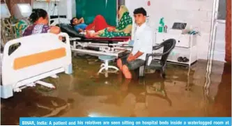  ??  ?? BIHAR, India: A patient and his relatives are seen sitting on hospital beds inside a waterlogge­d room at Nalanda Medical College and Hospital following heavy rains, in Patna in the Indian state of Bihar. — AFP