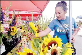  ?? NWA Democrat-Gazette/BEN GOFF @NWABENGOFF ?? Lucy Lee of Sulphur Springs looks at flowers for sale at the Xiong's Farm booth on Sunday at the Bella Vista Farmers' Market in the parking lot of Mercy Bella Vista. Xiong's Farm has locations in Gravette and Decatur.