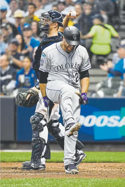  ??  ?? Rockies catcher Chris Iannetta breaks his bat over his knee after striking out against Milwaukee reliever Joakim Soria in the seventh inning at Miller Park during Game 2 of the NLDS on Friday.