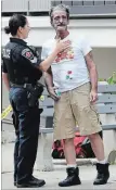  ?? HAMILTON SPECTATOR FILE PHOTO ?? A police officer holds back Wayne Bell after a fire at 200 Jackson St. W. in 2016.