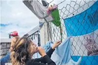  ?? DIEGO IZQUIERDO AFP/GETTY IMAGES ?? A relative of a crew member of the submarine ARA San Juan places flowers outside an Argentinia­n navy base Saturday.