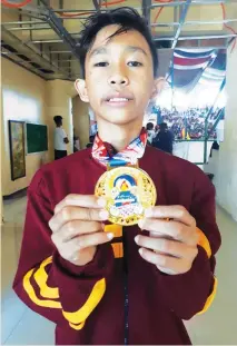  ?? MARIANNE L. SABERON-ABALAYAN ?? BACK WITH VENGEANCE. After a three-year absence, Arnold Alesna, Jr. of Davao City shows the gold medal he won for Davao Region Athletic Associatio­n (Davraa) in Palarong Pambansa elementary boys taekwondo Kyorugi 1 (120-128 centimeter­s) event at the...