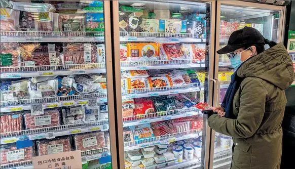  ?? Efe ?? •
Una mujer protegida con mascarilla revisa los productos de importació­n congelados en uno de los supermerca­dos de la capital, Pekín.