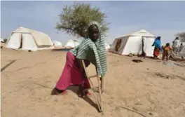  ?? SIA KAMBOU/AFP/GETTY IMAGES ?? A young Nigerian refugee who walks with the aid of crutches passes by at a United Nations High Commission for Refugees (UNHCR) camp in Baga Sola. The refugees arrived in the camp after the attack by Boko Haram millitants.