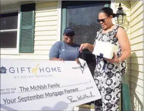  ?? Ned Gerard / Hearst Connecticu­t Media ?? Melissa Mason, left, branch manager for Envoy Mortgage in Fairfield, presents a check to Irana McNish on the front steps of her home in Derby on Tuesday. Envoy is covering McNish’s monthly mortgage payment to honor her for working as a nursing assistant during the COVID-19 pandemic. McNish works at Edgehill Rehabilita­tion in Stamford.