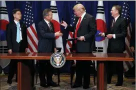  ?? EVAN VUCCI — THE ASSOCIATED PRESS ?? President Donald Trump hands a pen to South Korean President Moon Jae-In during a signing ceremony for the United States-Korea Free Trade Agreement at the Lotte New York Palace hotel during the United Nations General Assembly, Monday in New York.