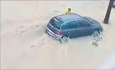  ?? . ?? El hombre intenta agarrarse a un coche antes de que la riada lo arrastre hasta el mar