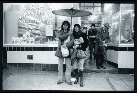  ??  ?? A man known as Blackie shelters his girlfriend outside Kwong Hing Co. Vegetables. Photograph­er Jim Wong-Chu liked the fact he was holding a Chinese parasol.