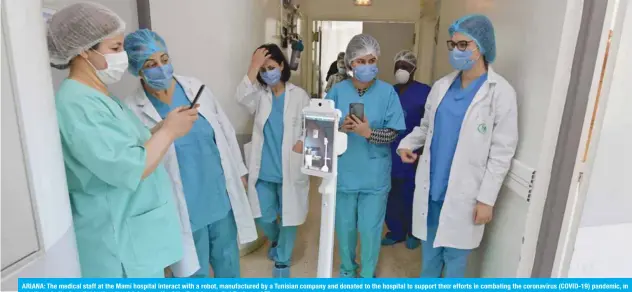  ?? — AFP ?? ARIANA: The medical staff at the Mami hospital interact with a robot, manufactur­ed by a Tunisian company and donated to the hospital to support their efforts in combating the coronaviru­s (COVID-19) pandemic, in a hallway in the hospital in the city of Ariana north of the Tunisian capital Tunis.