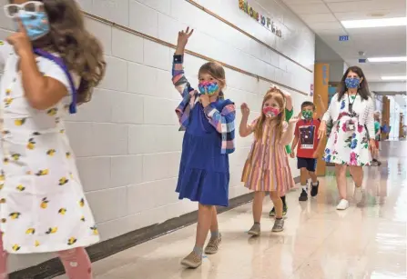  ?? LIZ DUFOUR/CINCINNATI ENQUIRER ?? First graders in Julie Fischer’s class at J.F. Burns Elementary School in the Kings Local school district head to their school special in August. Shortly after school started, the school board voted to mandate masks for pre-kindergart­en through sixth grade students due to increased numbers of COVID-19 cases and the delta variant.