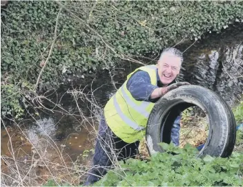  ??  ?? Cllr Sanders clears the tyres from the dyke