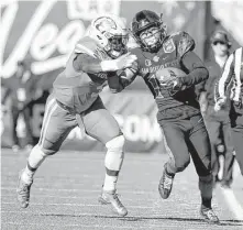  ??  ?? San Diego State’s Donnel Pumphrey runs past UH’s Matthew Adams on his way to setting the NCAA rushing mark Saturday.