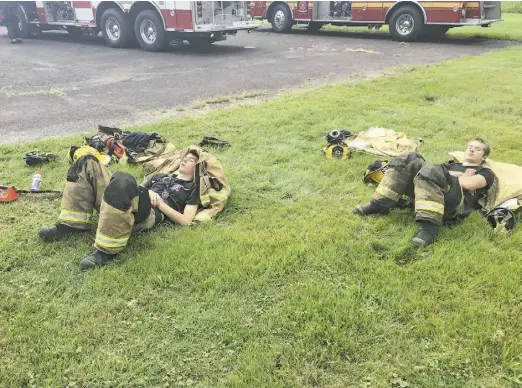  ?? BY JOHN MCCASLIN ?? Having battled flames through the night, a pair of young firefighte­rs from Little Fork Volunteer Fire in Rixeyville fall sound asleep on the grass a safe distance from the still-raging fire.