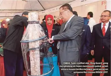  ??  ?? ISMAIL Sabri melihat alat ‘Ring Guard’ yang menghalang air hujan membasahi pokok getah antara inovasi ketika melawat gerai pameran
sempena Hari Inovasi RISDA 2017.