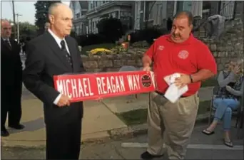  ?? KEVIN TUSTIN – DIGITAL FIRST MEDIA ?? Sharon Hill Mayor Harry Dunfee and Fire Chief William Benecke hold up a street sign that was presented to the Reagan family.