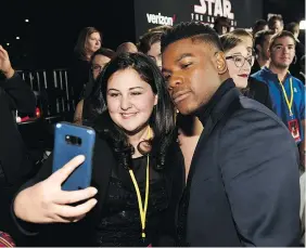  ??  ?? Olivia Sava, 14, takes a selfie with Star Wars: The Last Jedi cast member John Boyega. Sava, who suffers from a form of leukemia, said her dad got her interested in Star Wars when she was little.