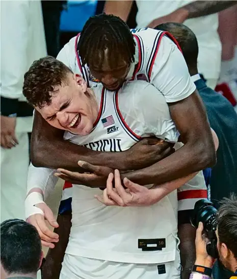  ?? ROSS D. FRANKLIN/ASSOCIATED PRESS ?? Alex Karaban (14 points, eight rebounds) got a hug from Youssouf Singare after defending champion UConn beat Alabama, 86-72, to reach Monday’s national title game against Purdue. NCAA coverage, C12.