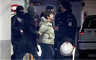 ??  ?? Panagiota Roupa, a leading member of the militant Revolution­ary Struggle organizati­on, is escorted by anti-terrorist police officers to a court in Athens following her arrest in the early hours of yesterday morning.