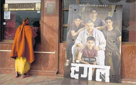  ?? Tsering Topgyal Associated Press ?? A MOVIEGOER in New Delhi buys a ticket beside a poster for the Indian film “Dangal,” which topped the Chinese box office last week.