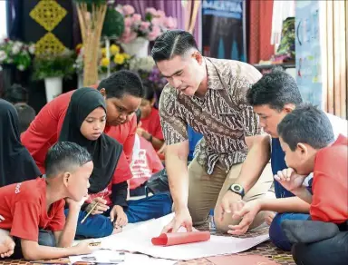  ??  ?? Cikgu AG (in brown batik) guiding his pupils to make Teachers’ Day cards to present to their teachers.