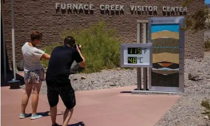  ?? California. Photograph: Ty ONeil/AP ?? People stop to take photos of a thermostat reading 119F (48C) at the Furnace Creek visitor center on Tuesday in Death Valley national park,