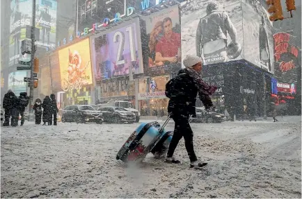  ?? PHOTO: AP ?? Kiwi Rebecca Hollis drags her suitcases in a snowstorm through Times Square on her way to a hotel in New York CIty yesterday.