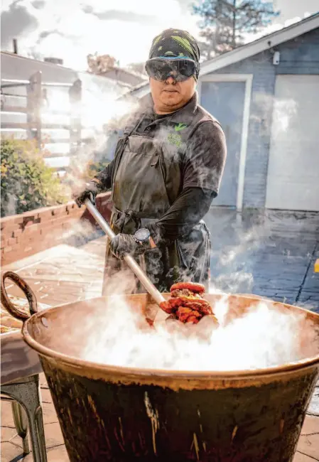  ?? Photos by LiPo Ching/Special to The Chronicle ?? Juan Ballona, above, suits up in protective gear to avoid hot oil splashes as he cooks up chicharron­es in a cauldron in the driveway of his San Jose home. His business took off when his wife posted pictures of the porcine product, left, on TikTok.