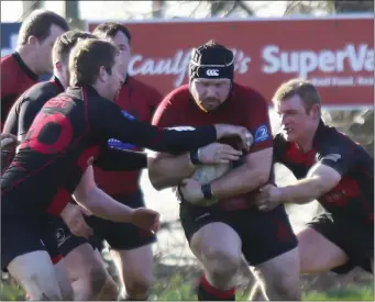  ??  ?? Foley Phillips of New Ross protects the ball from two would-be Arklow tacklers.